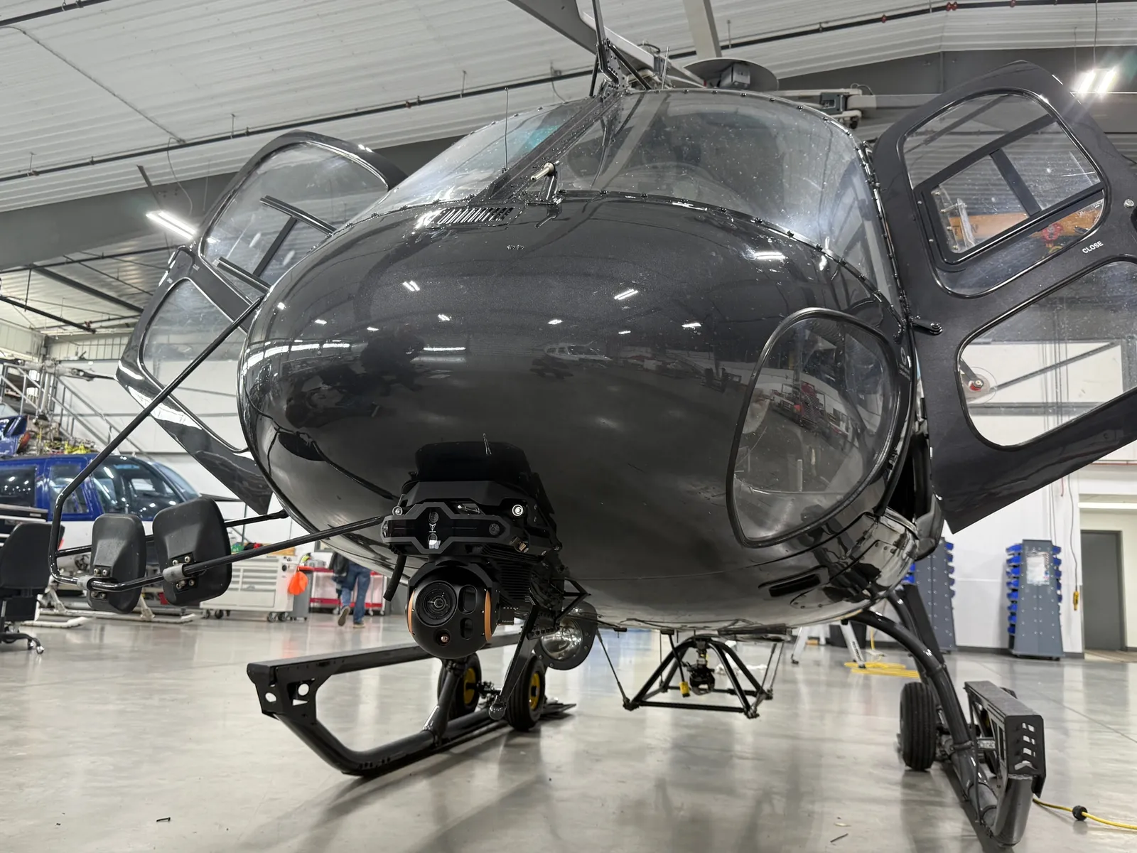 VoxVision cameras and onboard computing installed beneath an AS350 helicopter in a hangar.