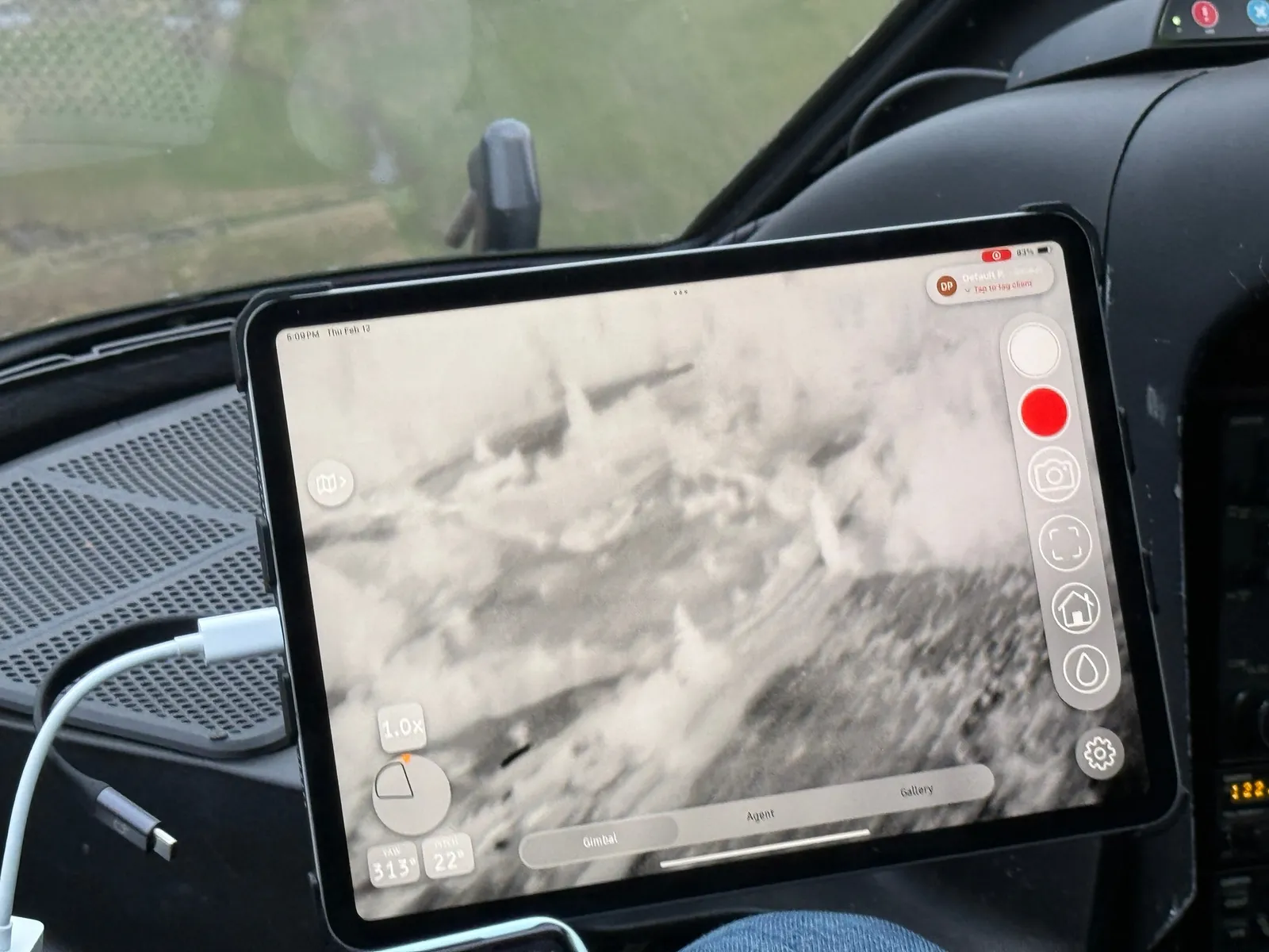 A tablet in an aircraft cockpit displaying a thermal view of the terrain.